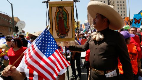 An immigrant wearing a traditional charro hat from Mexico, right, holds a banner of Mexico's Virgin of Guadalupe, as they gather to march during a May Day rally in downtown Los Angeles on Wednesday, May 1, 2013. In celebration of May Day, people have gathered across the country to rally for various topics including immigration reform. (AP Photo/Damian Dovarganes)