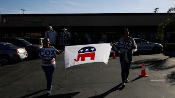 Two supporters carry a flag made with the elephant symbol of the Republican party while waiting for the arrival of gubernatorial candidate John Cox and Young Kim, a candidate running for a U.S. House seat in the 39th District in California, at a campaign stop Saturday, Nov. 3, 2018, in Rowland Heights, Calif. California's gubernatorial candidates target Orange County on Saturday, a place where Democrats hope to turn over four congressional seats. (AP Photo/Jae C. Hong)