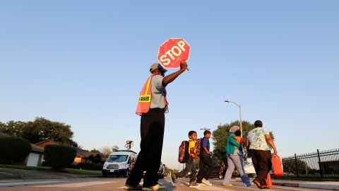 Crossing guard Frank Dewalt helps students and parents cross the street in front of Codwell Elementary School Monday, Sept. 11, 2017, in Houston. Students in Houston are finally starting their new school year following a two-week delay because of damage from Harvey. (AP Photo/David J. Phillip)