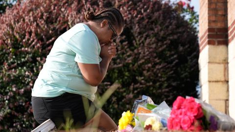 Linda Carter, of Grayson, Ga., kneels near Apalachee High School to place flowers as she mourners for the slain students and teachers on Thursday, Sept. 5, 2024, in Winder, Ga. (AP Photo/Brynn Anderson)