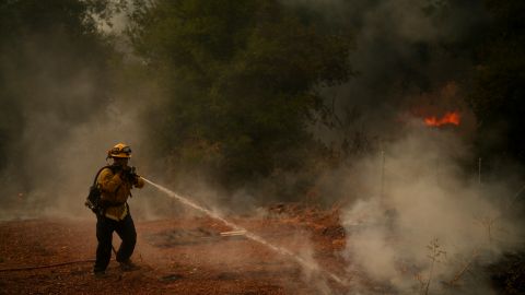 Un bombero rocía agua a una propiedad en llamas mientras lucha contra el incendio Aeropuerto.