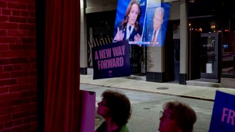 Laurie Kelly, right, and sister Diane Scharf, supporting Democratic presidential nominee Vice President Kamala Harris, watch the presidential debate reflected in the window between Harris and Republican presidential nominee former President Donald Trump, Tuesday, Sept. 10, 2024, at Alley Cat in Providence, R.I. (AP Photo/David Goldman)