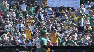 Oakland Athletics fans cheer after Brent Rooker, foreground, hit a single during the third inning of a baseball game against the Texas Rangers, Thursday, Sept. 26, 2024, in Oakland, Calif. (AP Photo/Godofredo A. Vásquez)