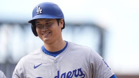 Los Angeles Dodgers' Shohei Ohtani smiles after reaching first base on a single off Colorado Rockies relief pitcher Seth Halvorsen in the eighth inning of a baseball game Sunday, Sept. 29, 2024, in Denver. (AP Photo/David Zalubowski)