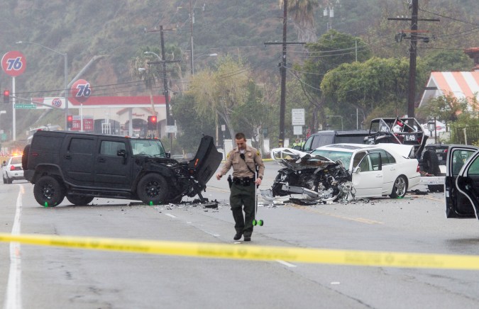 A Los Angeles County Sheriff's deputy investigates the scene of a collision involving three vehicles in Malibu, Calif. on Saturday, Feb. 7, 2015. Officials said former Olympian Bruce Jenner was a passenger in one of the cars involved in the Pacific Coast Highway crash that killed one person. Jenner's publicist, Alan Nierob, says Jenner was unhurt. (AP Photo/Ringo H.W. Chiu)