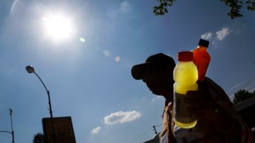 Michelle Dyer is silhouetted as she sells ice cold drinks along Ashland Avenue on Chicago's Southside as temperatures climb into the high 90's with the heat index breaking 100, Friday, July 19, 2013, in Chicago. (AP Photo/Charles Rex Arbogast)
