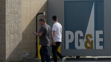 FILE - In this Feb. 20, 2020, file photo, pedestrians walk past a Pacific Gas and Electric sign at a PG&E location in San Francisco. Pacific Gas & Electric will face another legal challenge to a $13.5 billion settlement with more than 80,000 Northern California victims worried they're being shortchanged in a deal that's supposed to repay them for losses caused by the utility's negligence. (AP Photo/Jeff Chiu, File)