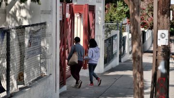 Parents take their children through the entrance of Hollenbeck Middle School in the Boyle Heights section of Los Angeles on Wednesday, Sept. 11, 2019. A student is recovering after being shot in the jaw at a Los Angeles middle school last month and officials say the boy was possibly struck by a bullet fired from off campus. The Los Angeles Times reports the student was injured Aug. 27, 2019, at Hollenbeck Middle School in Boyle Heights. Officials didn't publicly acknowledge the incident until Tuesday.(AP Photo/Richard Vogel)
