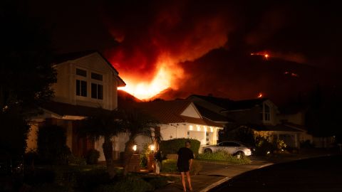 A man watches flames from the Airport Fire as it envelops a hill behind homes Monday, Sept. 9, 2024, in Trabuco Canyon, Calif. (AP Photo/Gregory Bull)