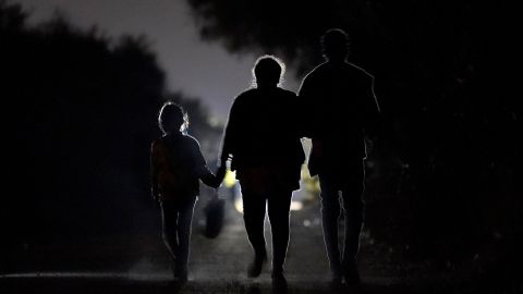 FILE - In this March 21, 2021, file photo a 7-year-old migrant girl from Honduras, left, walks with Fernanda Solis, 25, center, also of Honduras, and an unidentified man as they approach a U.S. Customs and Border Protection processing center to turn themselves in while seeking asylum moments after crossing the U.S.-Mexico border in Mission, Texas. The girl's journey illustrates the extraordinary risks taken by parents to get their children across the border, even if it means abandoning them for the most perilous part of the trip. She is one of thousands of kids arriving alone in the U.S. in a surge that is straining the federal government's system for managing refugees. (AP Photo/Julio Cortez)