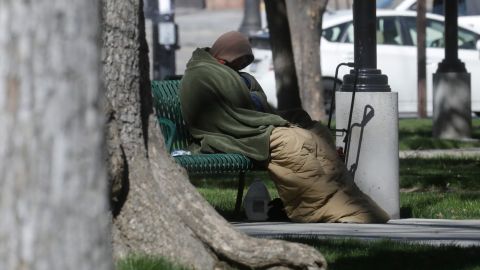 A man sits on a park bench Tuesday, April 14, 2020, in Salt Lake City. Salt Lake City is leasing a hotel to shelter homeless people over 60 with underlying health conditions who are particularly vulnerable to coronavirus infections. People began checking into the 130-bed hotel Friday and can stay for at least two weeks with a possible extension, said county Mayor Jenny Wilson. Salt Lake City has confirmed a handful of cases in the homeless community, where preventative steps such as hand-washing and social distancing are more difficult. (AP Photo/Rick Bowmer)