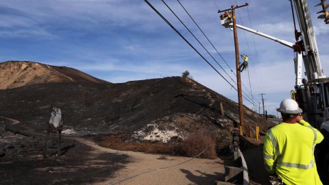 Southern California Edison crews work to replace burned power poles and lines destroyed by the Woolsey Fire over a burned-over hillside along Pacific Coast Highway in Malibu, southern California, Tuesday, Nov. 13, 2018. (AP Photo/Reed Saxon)