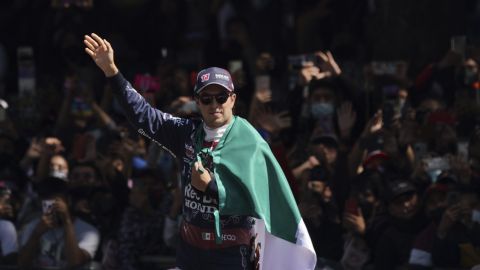 Mexican Formula One Red Bull driver Sergio "Checo" Perez waves as he holds his nation's flag after an exhibition race along Paseo de la Reforma ahead of this weekend's Mexico Grand Prix in Mexico City, Wednesday, Nov. 3, 2021. (AP Photo/Fernando Llano)