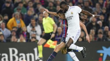 Barcelona's Robert Lewandowski and Real Madrid's Antonio Rudiger, right, compete for the ball during the Spanish La Liga soccer match between Barcelona and Real Madrid at Camp Nou stadium in Barcelona, Spain, Sunday, March 19, 2023. (AP Photo/Joan Mateu)