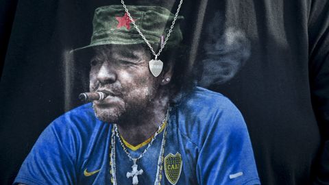 A Boca Juniors fan wears a T-shirt featuring the late soccer star Diego Maradona smoking a cigar and donning a red star beret, during an Argentine soccer league match against River Plate at La Bombonera stadium in Buenos Aires, Argentina, Saturday, Sept. 21, 2024.(AP Photo/Gustavo Garello)