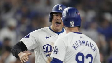 Los Angeles Dodgers' Shohei Ohtani celebrates with Kevin Kiermaier (93) after scoring on a double by Mookie Betts during the eighth inning in Game 1 of a baseball NL Championship Series against the New York Mets, Sunday, Oct. 13, 2024, in Los Angeles. (AP Photo/Ashley Landis)