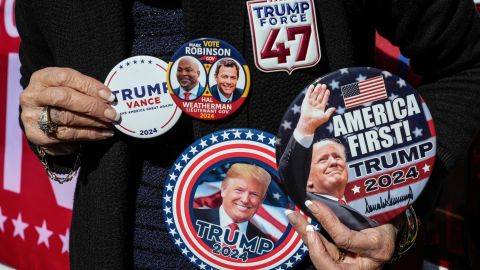 Ann McDonald of Rutherfordton, shows off her display of political buttons in support of the Republican ticket, former President Trump, Lt. Gov. Mark Robinson and Hal Weatherman, Thursday, Oct. 17, 2024, outside the Rutherford County Annex Building on the first day of early voting, in Rutherfordton, N.C. (AP Photo/Kathy Kmonicek)