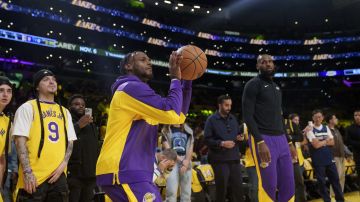 Los Angeles Lakers guard Bronny James, left, and forward LeBron James warm up before an NBA basketball game against the Minnesota Timberwolves, Tuesday, Oct. 22, 2024, in Los Angeles. (AP Photo/Eric Thayer)