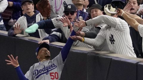 Fans interfere with a foul ball caught by Los Angeles Dodgers right fielder Mookie Betts during the first inning in Game 4 of the baseball World Series against the New York Yankees, Tuesday, Oct. 29, 2024, in New York. (AP Photo/Ashley Landis)