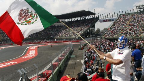 A man wearing a traditional Mexican wrestling mask waves a Mexican flag before the Formula One Mexico Grand Prix auto race at the Hermanos Rodriguez racetrack in Mexico City, Sunday, Nov. 1, 2015. (AP Photo/Moises Castillo)