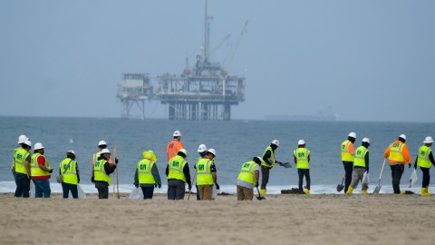 FILE - Workers in protective suits continue to clean the contaminated beach with a platform in the background in Huntington Beach, Calif., on Oct. 11, 2021. The owner of an underwater oil pipeline that spilled some 25,000 gallons of crude into the ocean off Southern California will pay nearly $1 million in cleanup costs. The Orange County Board of Supervisors on Tuesday, July 26, 2022 agreed to accept a proposed claim settlement with Amplify Energy Corp. over the costs of dealing with last October’s spill off Huntington Beach. (AP Photo/Ringo H.W. Chiu, File)