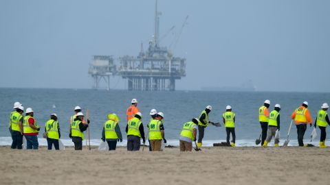 FILE - Workers in protective suits continue to clean the contaminated beach with a platform in the background in Huntington Beach, Calif., on Oct. 11, 2021. The owner of an underwater oil pipeline that spilled some 25,000 gallons of crude into the ocean off Southern California will pay nearly $1 million in cleanup costs. The Orange County Board of Supervisors on Tuesday, July 26, 2022 agreed to accept a proposed claim settlement with Amplify Energy Corp. over the costs of dealing with last October’s spill off Huntington Beach. (AP Photo/Ringo H.W. Chiu, File)