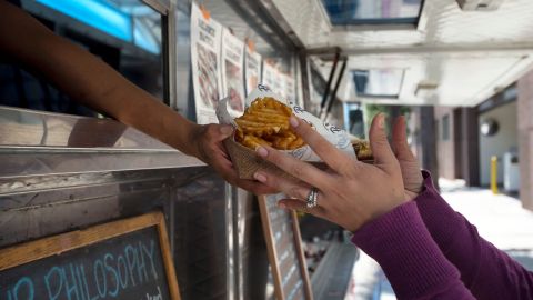 A customer picks up her order at the Peaches' Smokehouse & Southern Kitchen food truck, Friday, July 10, 2015, in Burbank, Calif. (AP Photo/Jae C. Hong)