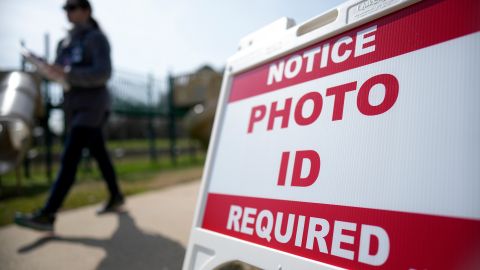 Un votante pasa junto a un cartel que exige una identificación con fotografía en un lugar de votación.