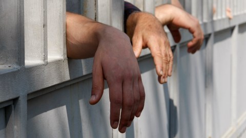 Relatives of inmates reach through a prison fence as they stand to see their family members during a protest rally against prison abuse in Tbilisi, Georgia, Friday, Sept. 21, 2012. Thousands rallied Friday in Georgia to demand the prosecution of top officials fired in a prison abuse scandal that threatens to unseat the governing pro-Western party in the country's Oct. 1 parliamentary election. (AP Photo/Shakh Aivazov)