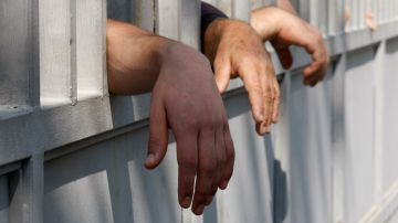Relatives of inmates reach through a prison fence as they stand to see their family members during a protest rally against prison abuse in Tbilisi, Georgia, Friday, Sept. 21, 2012. Thousands rallied Friday in Georgia to demand the prosecution of top officials fired in a prison abuse scandal that threatens to unseat the governing pro-Western party in the country's Oct. 1 parliamentary election. (AP Photo/Shakh Aivazov)