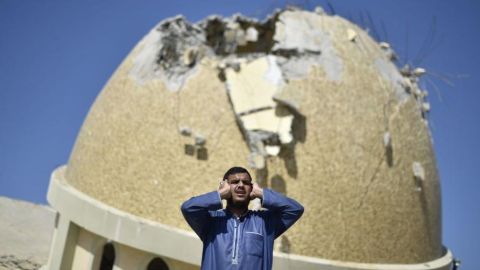 Un hombre reza frente a una mezquita destruida por los bombardeos de Israel en Gaza.