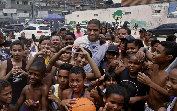 Italy's AS Roma's soccer player Adriano, of Brazil, top, is surrounded by children during the inauguration of community center Imperadores da Vila in the Vila Cruzeiro slum, his boyhood home, in Rio de Janeiro, Brazil, Wednesday Dec. 22, 2010. The center, funded by Adriano, is located in one of the slums raided by Brazilian police after five days of drug gang violence in November. (AP Photo/Felipe Dana)