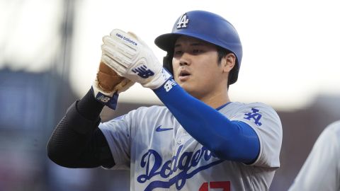 Los Angeles Dodgers' Shohei Ohtani cleans off his gloves after sliding back into first base on a pickoff attempt by Colorado Rockies pitcher Antonio Senzatela in the first inning of a baseball game, Saturday, Sept. 28, 2024, in Denver. (AP Photo/David Zalubowski)