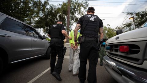 In this July 8, 2019, photo, a U.S. Immigration and Customs Enforcement (ICE) officers escort a man in handcuffs during an operation in Escondido, Calif. The carefully orchestrated arrest last week in this San Diego suburb illustrates how President Donald Trump's pledge to start deporting millions of people in the country illegally is virtually impossible with ICE's budget and its method of picking people up. (AP Photo/Gregory Bull)