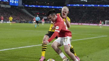 PSV's Hirving Lozano, right, vies for the ball with Dortmund's Julian Ryerson during the Champions League round of 16 first leg soccer match between PSV Eindhoven and Borussia Dortmund at Philips stadium in Eindhoven, Netherlands, Tuesday, Feb. 20, 2024. The match ended in a 1-1 draw. (AP Photo/Peter Dejong)