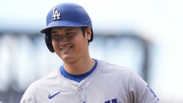 FILE - Los Angeles Dodgers' Shohei Ohtani smiles after reaching first base on a single off Colorado Rockies relief pitcher Seth Halvorsen in the eighth inning of a baseball game Sept. 29, 2024, in Denver. (AP Photo/David Zalubowski, File)