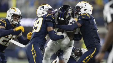 Baltimore Ravens running back Derrick Henry (22) runs with the ball as Los Angeles Chargers defenders tackle him during an NFL football game, Monday, Nov. 25, 2024, in Inglewood, Calif. (AP Photo/Kyusung Gong)