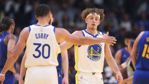 Golden State Warriors guard Stephen Curry, left, congratulates guard Brandin Podziemski after he made a basket and drew a foul shot against the Denver Nuggets in the first half of an Emirates NBA Cup basketball game Tuesday, Dec. 3, 2024, in Denver. (AP Photo/David Zalubowski)