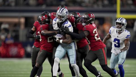 Dallas Cowboys wide receiver CeeDee Lamb (88) is stopped after a catch by Tampa Bay Buccaneers' Christian Izien, left, Jamel Dean, center rear, and Tykee Smith, right, in the first half of an NFL football game in Arlington, Texas, Sunday, Dec. 22, 2024. (AP Photo/Julio Cortez)