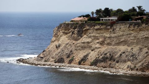 This July 12, 2016, photo shows large homes atop a bluff at Rocky Point, where a small stone structure is seen at lower left, in Lunada Bay in the tiny, seaside city of Palos Verdes Estates, Calif. The days are numbered for the "Stone Fort," created by a territorial group of surfers known as the Bay Boys, erected illegally decades ago as part of their sustained battle to keep rival wave-riders from some of the best breaks in Southern California. The city, under pressure from the California Coastal Commission and others, Tuesday, July 12, 2016 ordered the structure torn down amid complaints that its only purpose is as a staging area from which the Bay Boys can gather to harass other surfers. (AP Photo/Reed Saxon)