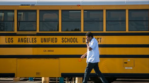 FILE - A Los Angeles Unified School District bus driver walks past parked vehicles at a bus garage in Gardena, Calif., on Dec. 15, 2015. Tens of thousands of workers in the Los Angeles Unified School District will strike for three days next week over stalled contract talks and teachers will join them, likely shutting down the nation's second-largest school system, union leaders announced Wednesday, March 15, 2023. (AP Photo/Damian Dovarganes, File)