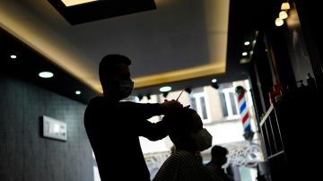 A client, wearing a face mask to prevent against the spread of coronavirus, gets his hair styled at a hairdresser's shop in Brussels, Tuesday, Feb. 16, 2021. The Belgium government allowed to reopen hairdresser and barber shops but with some conditions due to the COVID-19 coronavirus spread. (AP Photo/Francisco Seco)