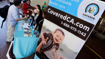 FILE - In this Oct. 1, 2013, file photo, an information table is busy at Union Station in downtown Los Angeles as people seek information on state-provided health insurance, while a celebration is underway to inaugurate the first day people can enroll. Officials with California's health insurance exchange said Tuesday, Jan. 21, 2014, that about 625,000 people have signed up for an individual or family policy under the federal health care reforms, but enrollments for Latinos and younger people continue to lag expectations. (AP Photo/Reed Saxon, File)