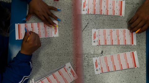 Nancy Linares, left, and Prince Joseph Israel fill out Mega Millions play slips at Blue Bird Liquor in Hawthorne, Calif., Tuesday, July 26, 2022. Lottery players will be gripping their tickets tightly ahead of the Tuesday night's Mega Millions drawing with an estimated $830 million prize on the line. (AP Photo/Jae C. Hong)