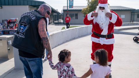 Un voluntario lleva a dos pequeñas a escoger sus regalos de Navidad.