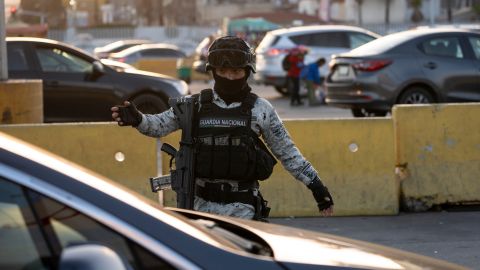 A member of the Mexican National Guard reviews cars as they line up to cross the border into the United States at the San Ysidro Port of Entry, Tuesday, Dec. 3, 2024, in Tijuana, Mexico. (AP Photo/Gregory Bull)