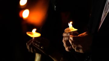 People hold candles during an outdoor Service of Lights Christmas Eve service at the Granada Presbyterian Church, Thursday, Dec. 24, 2020, in Coral Gables, Fla. The service was held outdoors for safety reasons to protect against the spread of the coronavirus. (AP Photo/Lynne Sladky)