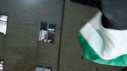 Un hombre ondea banderas palestinas ante las noticias sobre un acuerdo de alto el fuego con Israel.