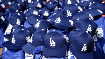 Los Angeles Dodger caps to be distributed to fans sit in a pile before the Dodger Day Drive-Thru at Belvedere Park, Tuesday, June 30, 2020, in Los Angeles. The event was hosted by The Los Angeles Dodgers Foundation, which distributed food boxes, books, sports equipment, clothing, toys and hygiene supplies to over 1000 registered youth from the Boyle Heights, East Los Angeles, La Puente and Monterey Park communities. (AP Photo/Chris Pizzello)