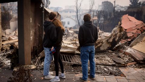 Residents embrace in front of a fire-ravaged property after the Palisades Fire swept through in the Pacific Palisades neighborhood of Los Angeles, Wednesday, Jan. 8, 2025. (AP Photo/Etienne Laurent)